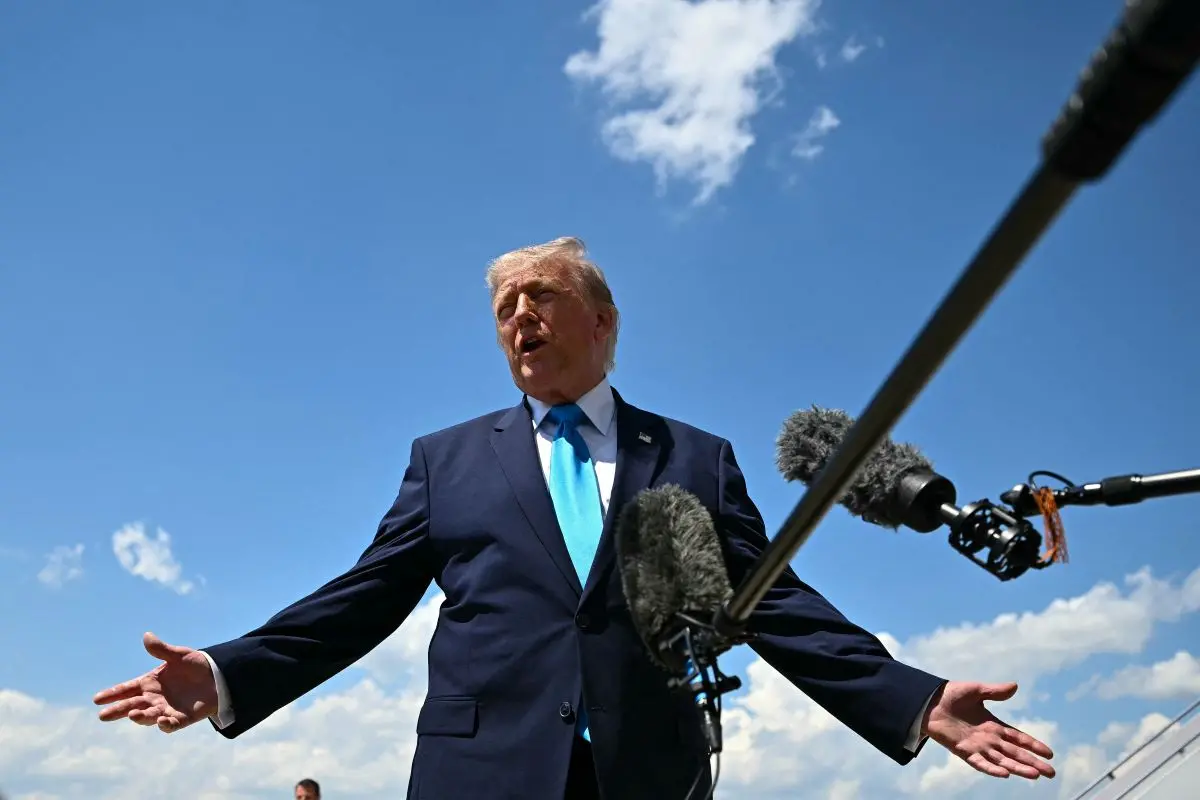 Trump fala ao ar livre durante entrevista, com microfones apontados e céu azul ao fundo.