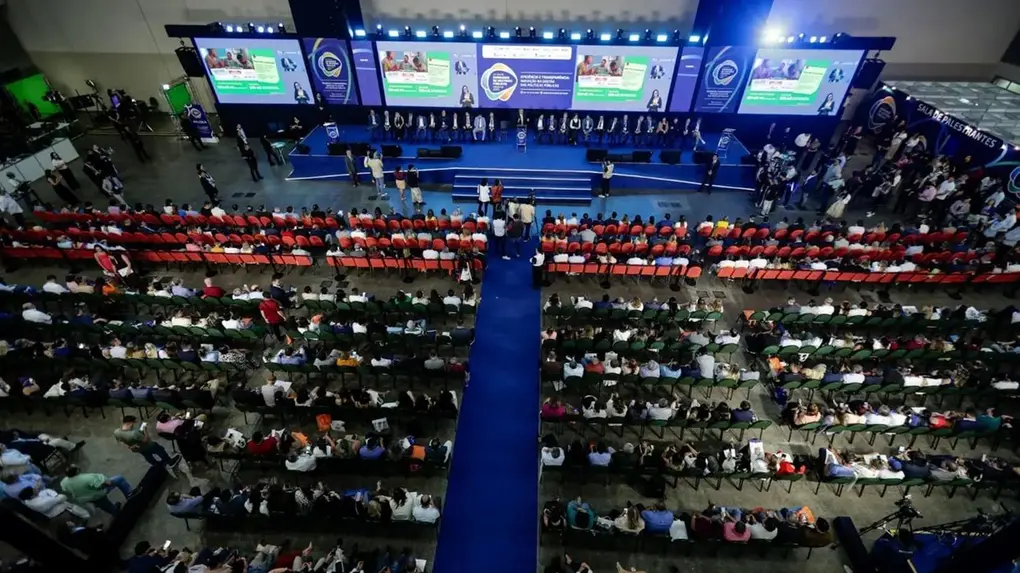 Imagem mostra palco com dezenas de espectadores que assistem a palestras do Seminário de Prefeitos.