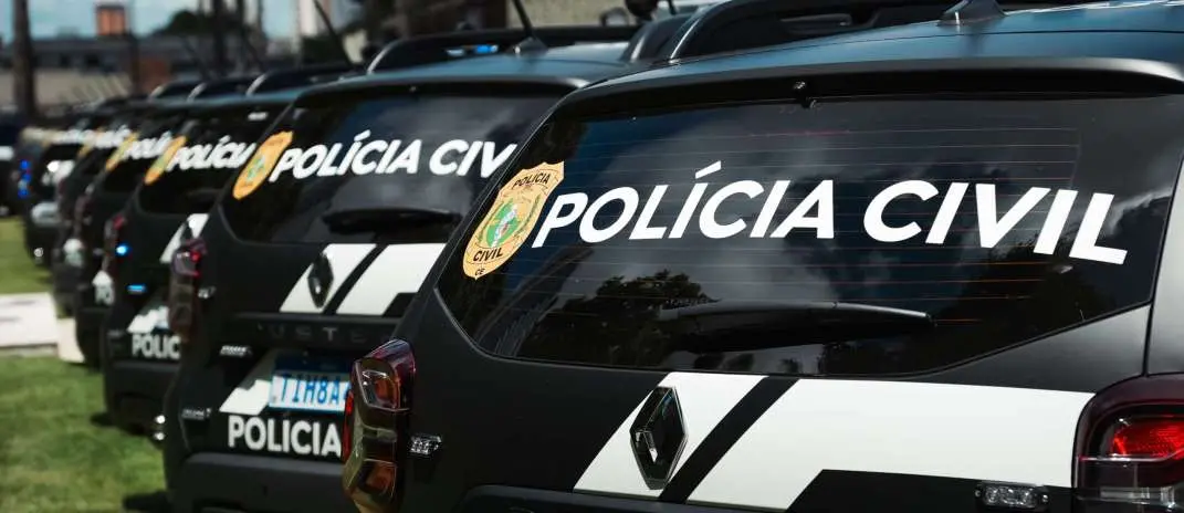 Várias viaturas pretas da Polícia Civil do Ceará estão enfileiradas em um pátio externo durante o dia, com destaque para a traseira do veículo em primeiro plano. O vidro traseiro exibe a inscrição 'POLÍCIA CIVIL' em letras brancas grandes e o brasão oficial da corporação.