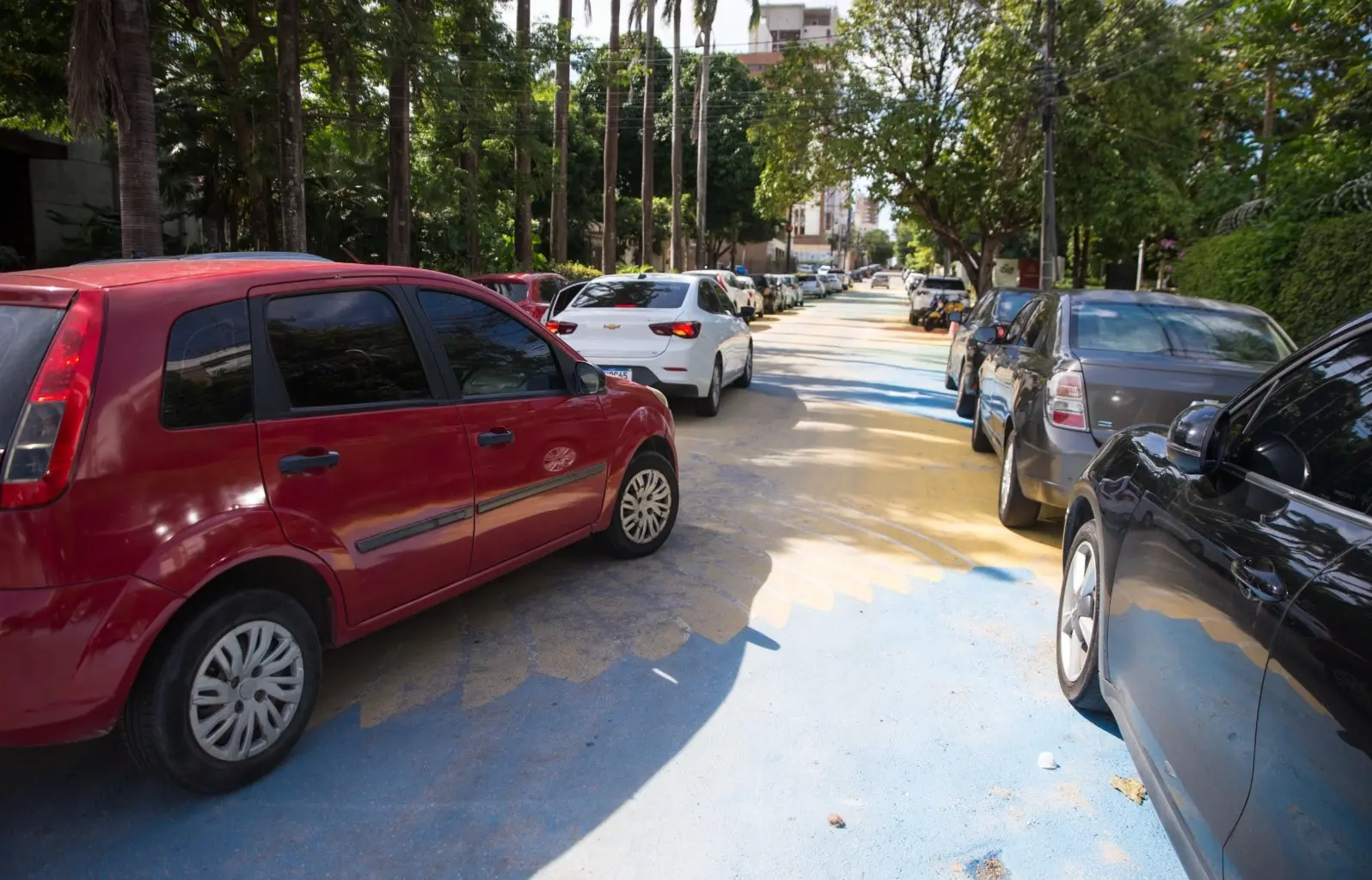 Carros trafegam em rua pintada com as cores do Brasil para a Copa do Mundo.