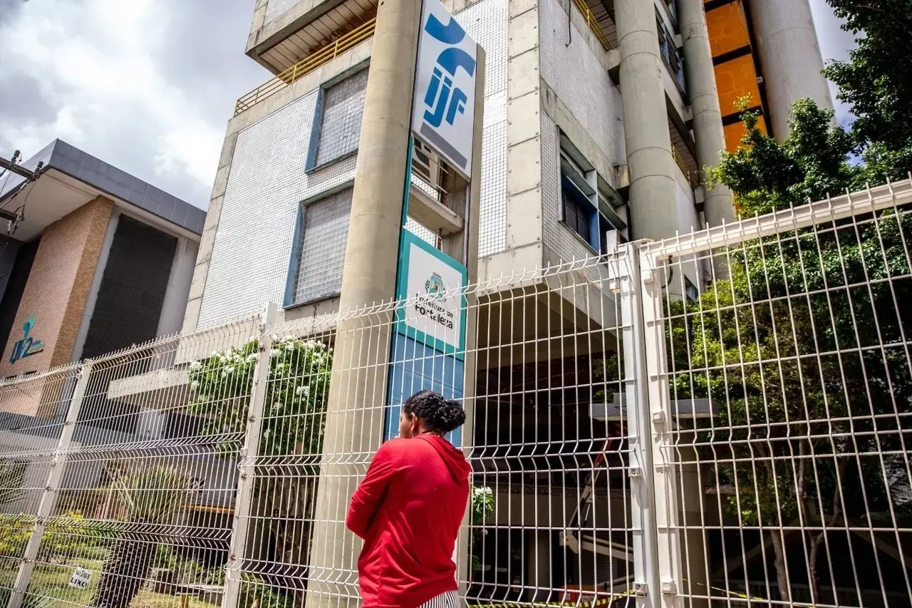 Foto de mulher perto do letreiro com IJF escrito.
