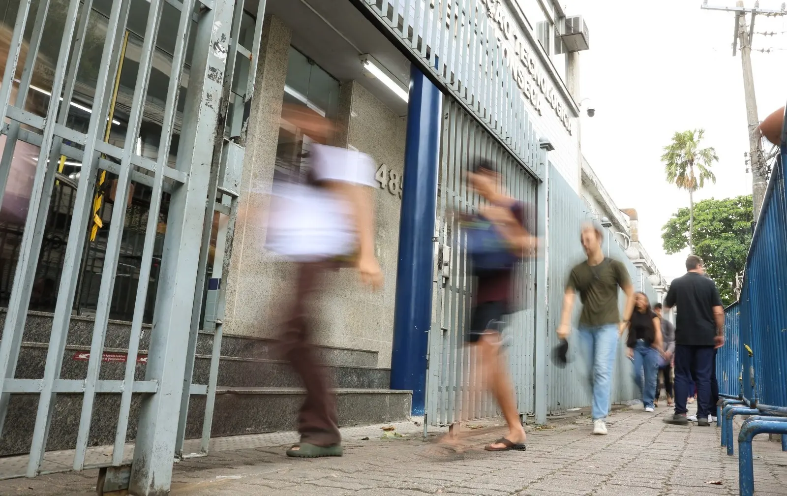 Imagem borrada de candidatos ao Enem entrando e saindo de um local de prova.