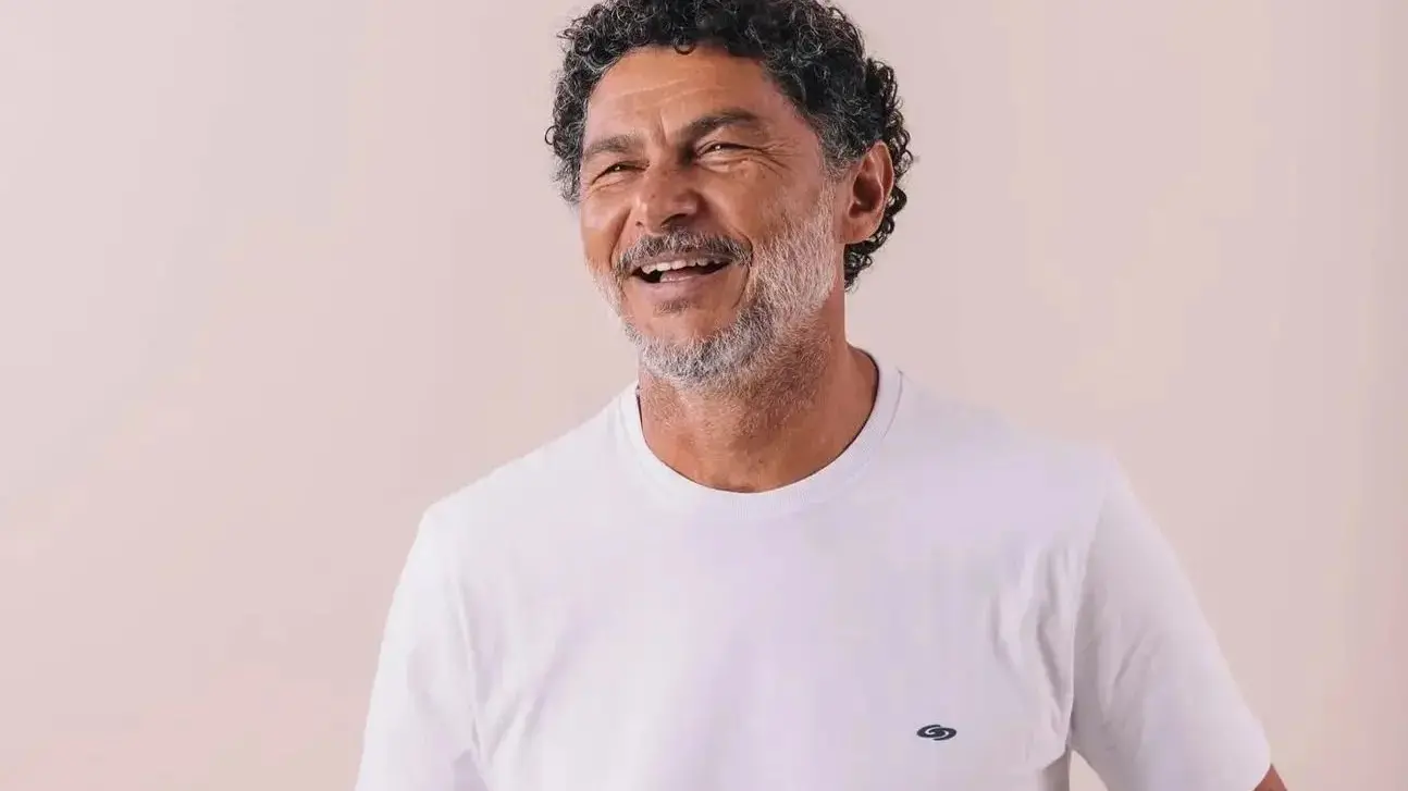 Petrônio era um homem de meia idade, de cabelo cacheado preto com alguns fios brancos. Na foto, ele está de camiseta branca, sorrindo.