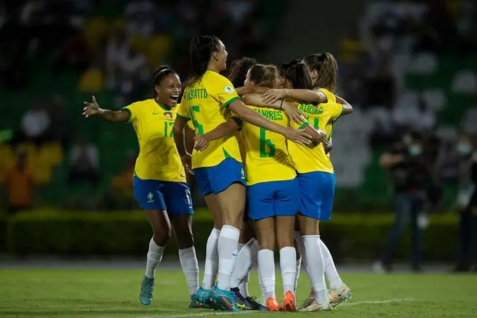 Imagem mostra jogadoras de futebol em abraço.