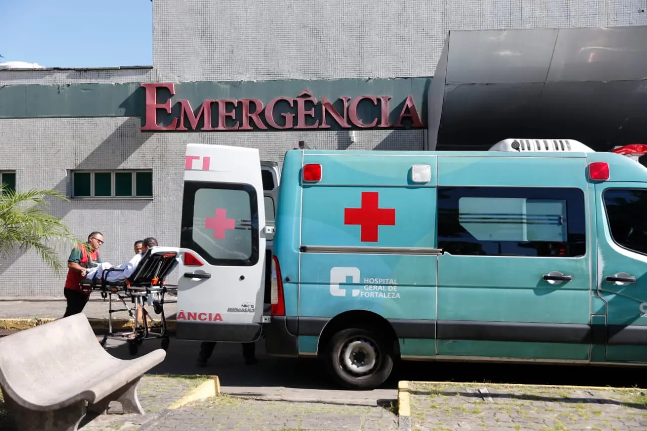 Paciente em uma maca sendo retirado de ambulância em frente à entrada da emergência do Hospital Geral de Fortaleza.