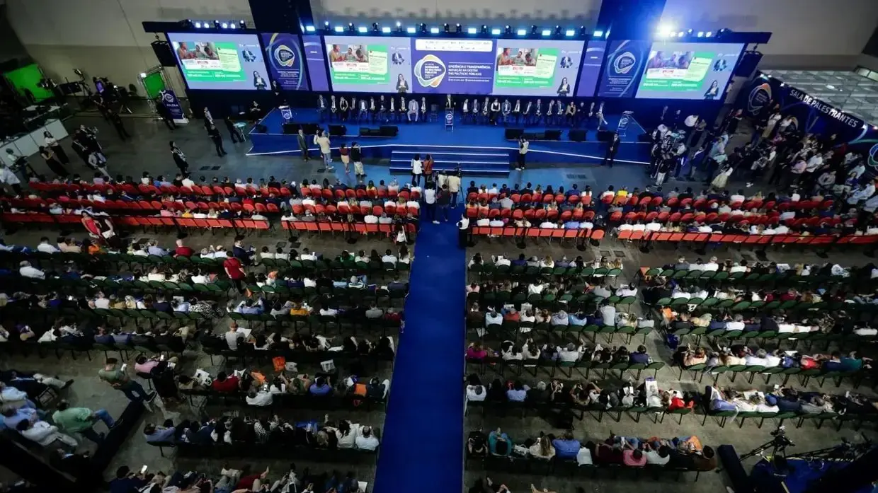 Imagem mostra palco com dezenas de espectadores que assistem a palestras do Seminário de Prefeitos.