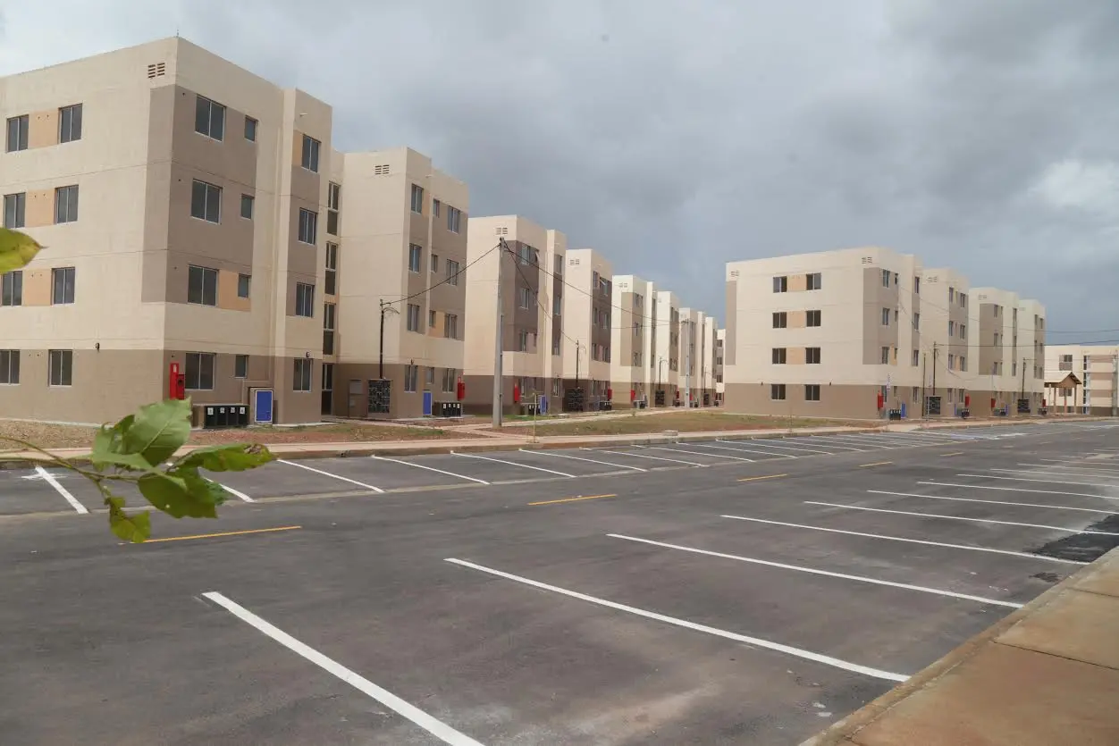 Pátio e estacionamento com vagas demarcadas em frente a um conjunto de prédios residenciais ou de apartamentos em bairro planejado, sob céu nublado.