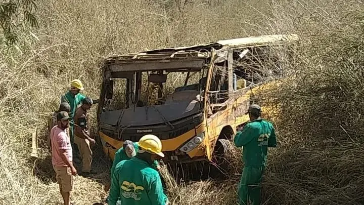 Foto de ônibus escolar amarelo destruído em meio a vegetação seca no interior do Ceará, com homens de uniforme verde tentando resgatar vítimas.