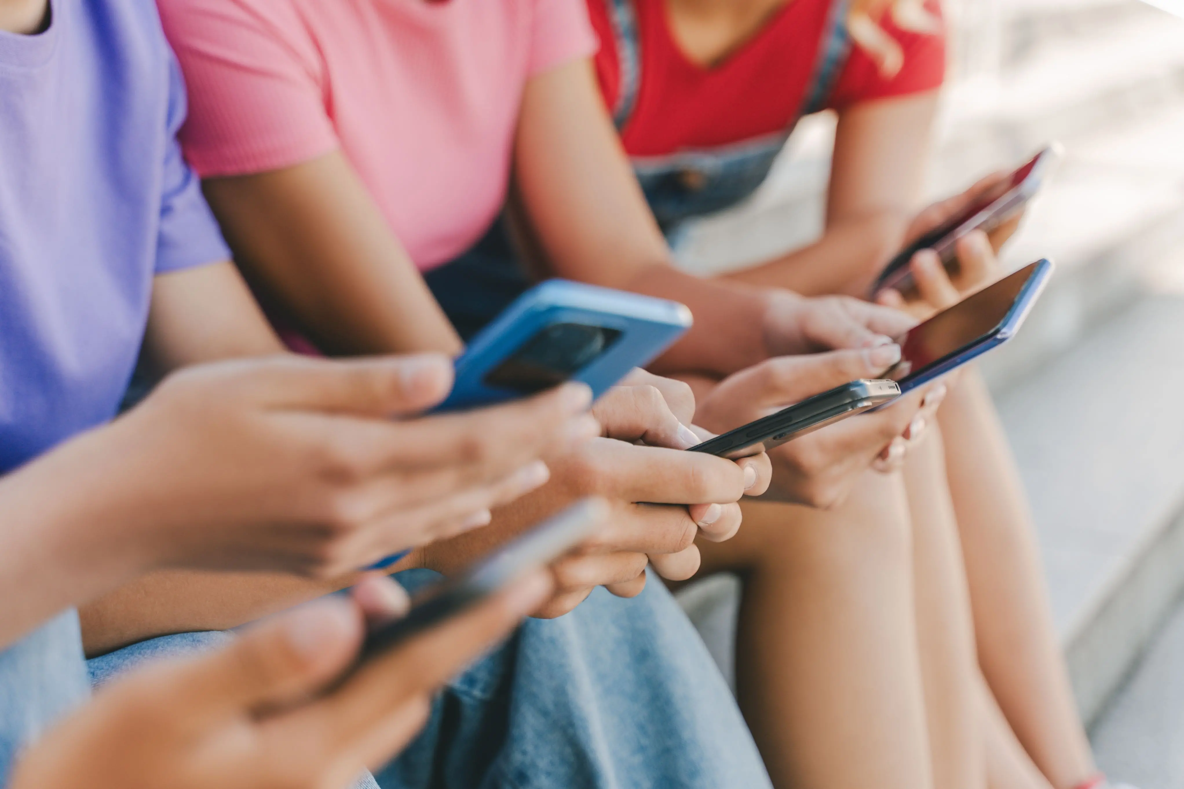 Imagem de crianças usando o celular para ilustrar uma matéria sobre influenciadores menores de 16 anos.
