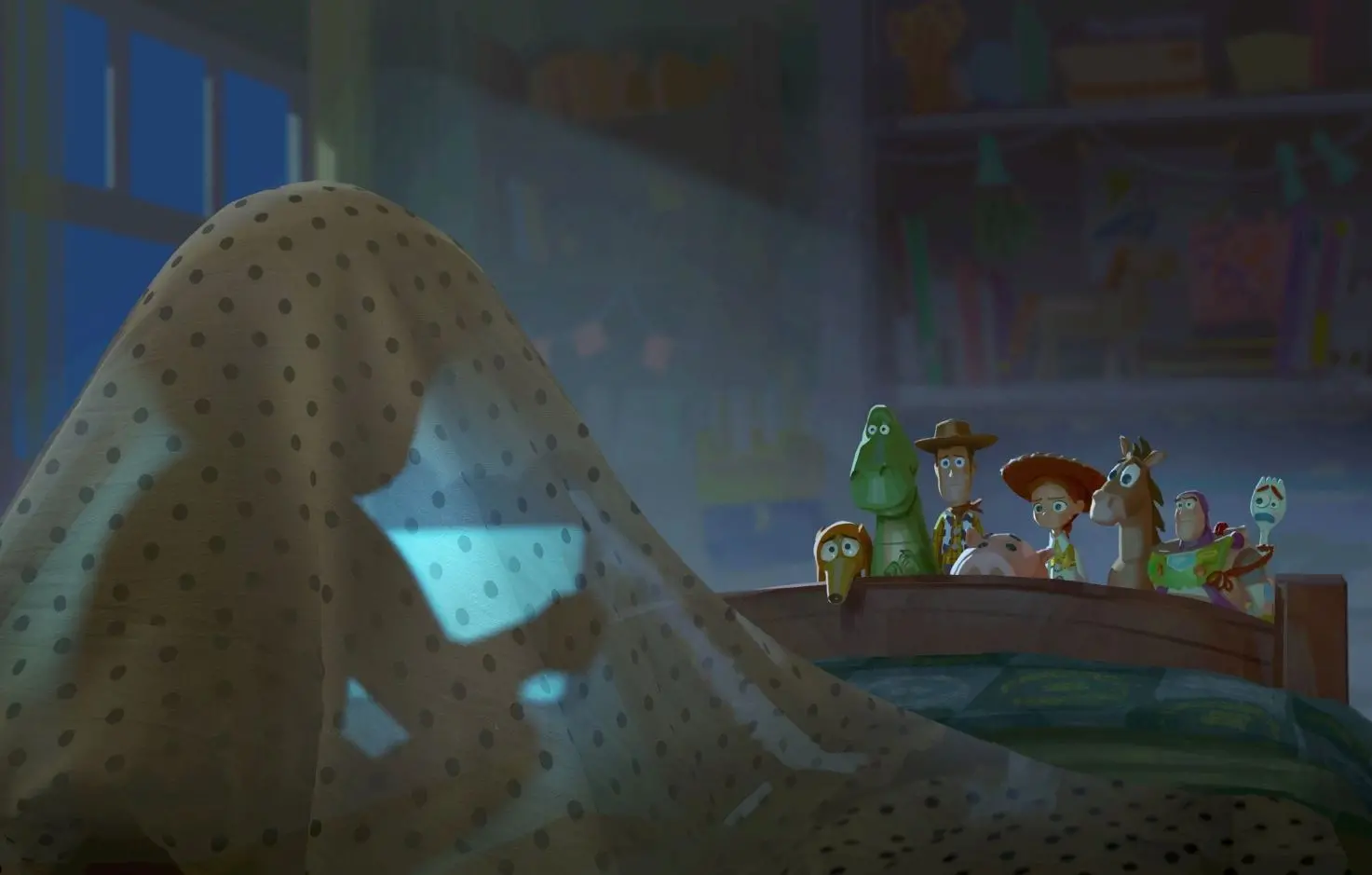 Cena animada em quarto infantil mostra brinquedos alinhados na lateral de uma cama observando um lençol com estampa de bolinhas erguido como um “fantasma”, iluminado por luz azul suave.