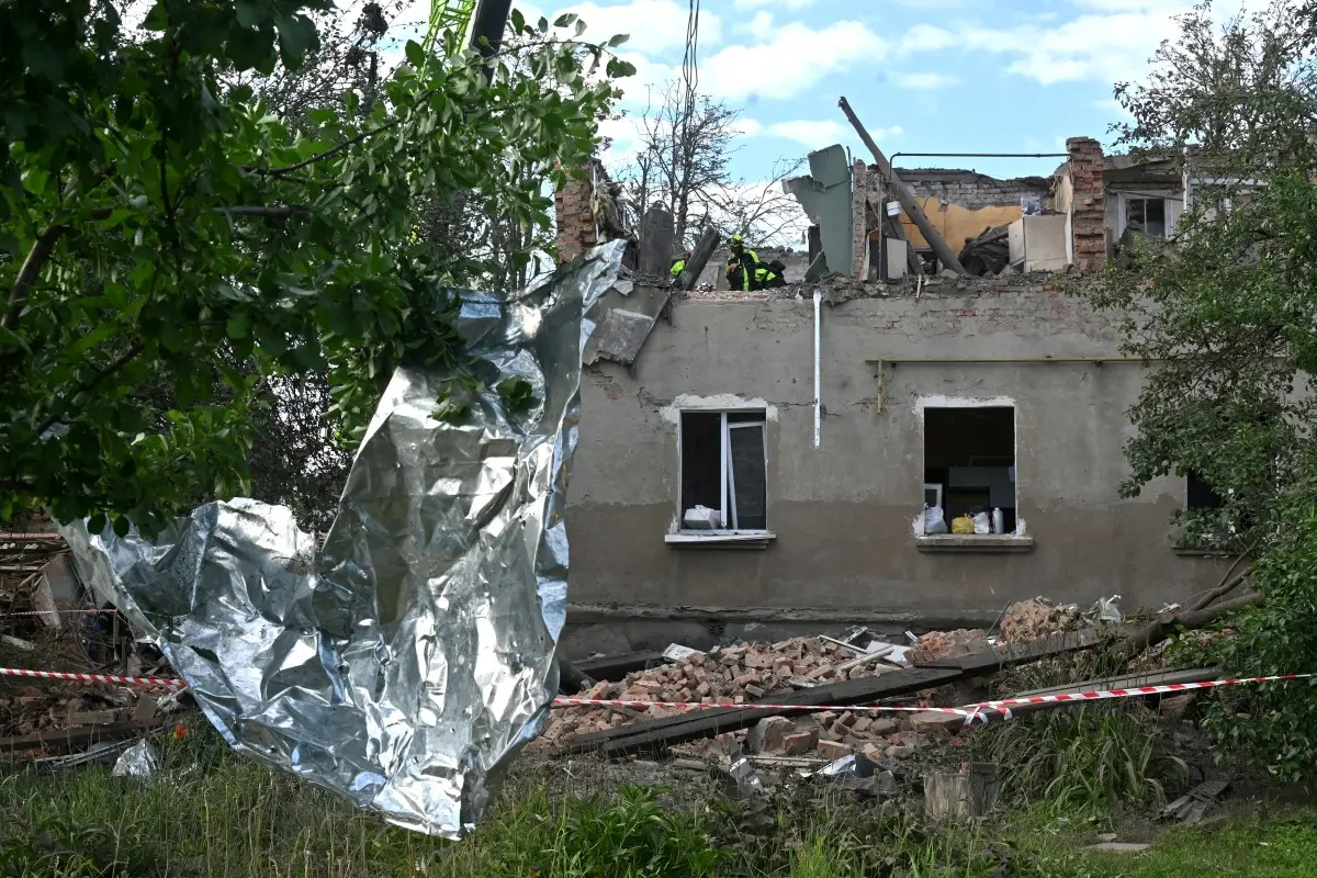 Casa parcialmente destruída aparece cercada por escombros após um ataque. Parte do telhado e das paredes desabou, deixando o interior exposto.