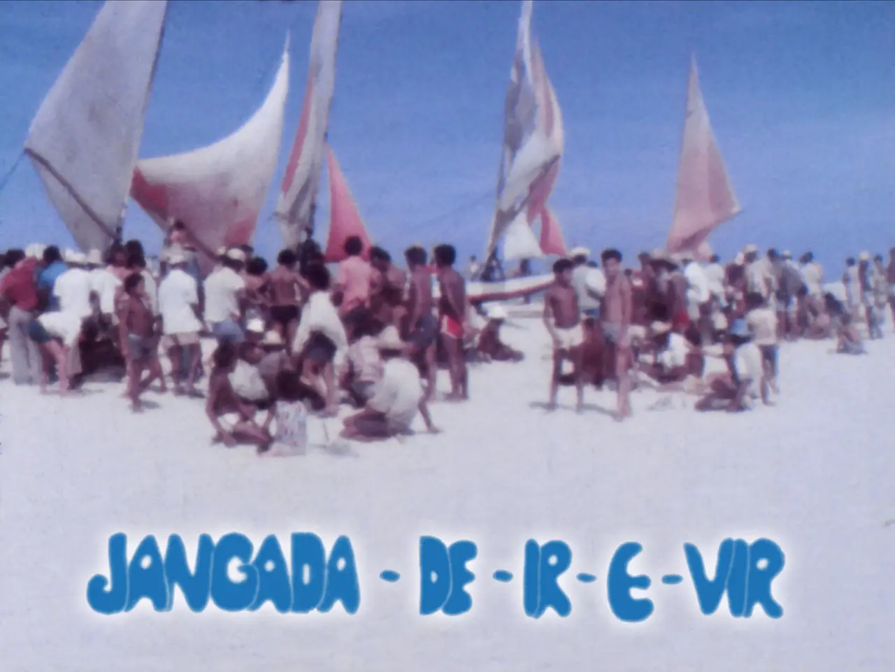 Uma grande quantidade de pessoas se reúne na areia clara de uma praia ao lado de várias jangadas com velas içadas sob o céu azul. Na parte inferior da imagem, destaca-se o título estilizado 'JANGADA - DE - IR - E - VIR' escrito em letras azuis com contorno branco.