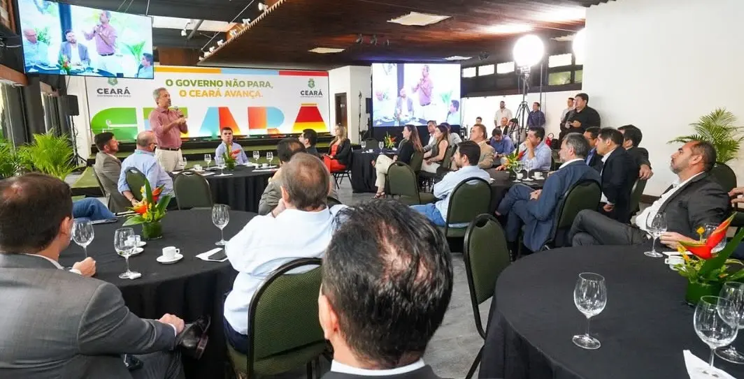Autoridades, parlamentares e representantes do setor produtivo participam de reunião em um auditório, organizados em mesas redondas.