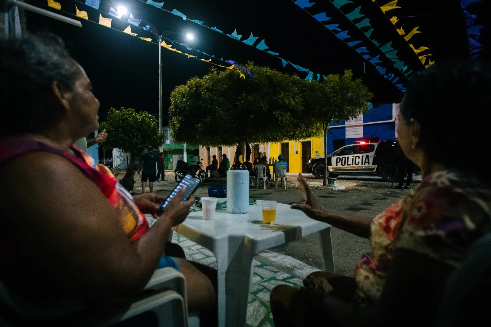 Pessoas conversando, bebendo e rindo em mesa de bar 