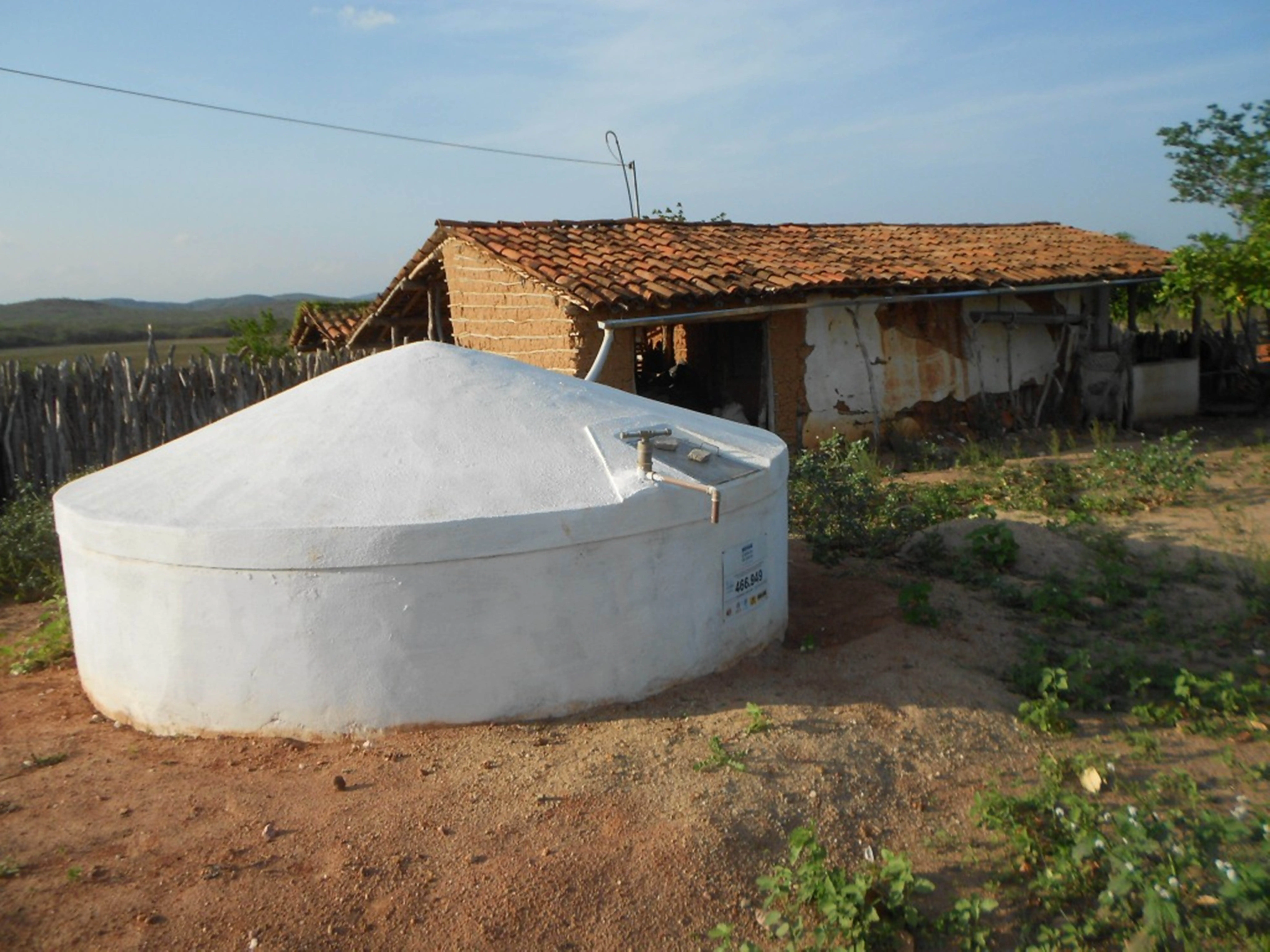 Foto de cisterna ao lado de casa em área rural.