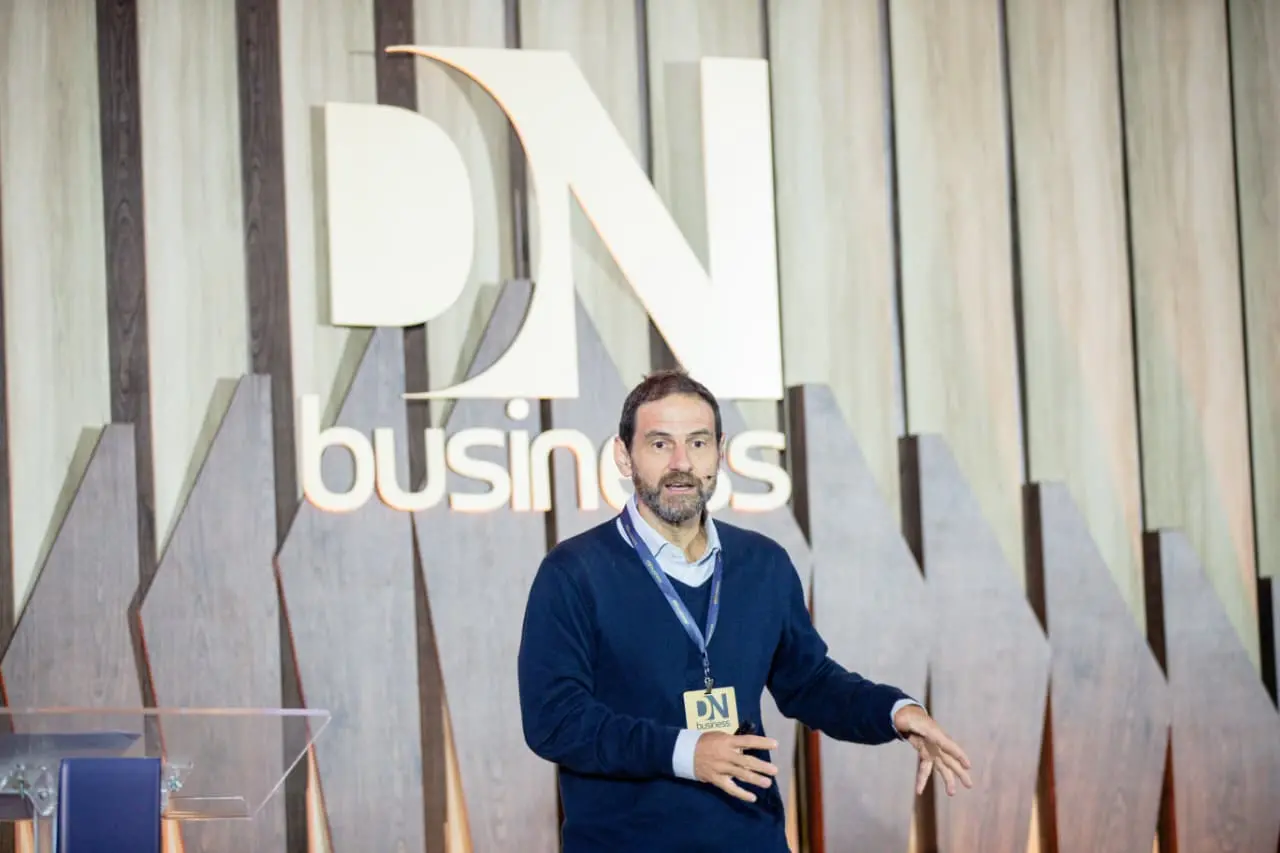 Foto que contém Caio Megale, economista-chefe da XP Investimentos. Ele é um homem branco, alto, com cabelo escuro e barba grisalha, e veste blusa azul-escuro.