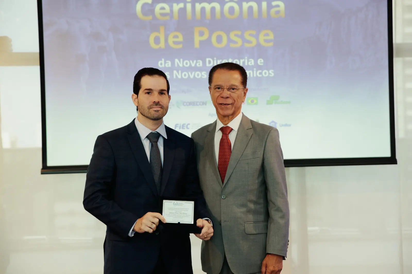 Felipe Queiroz recebendo a homenagem por Yolanda Queiroz, in memoriam, durante a cerimônia de posse da Academia Cearense de Economia. Ao seu lado, o economista Sérgio Silveira Melo.