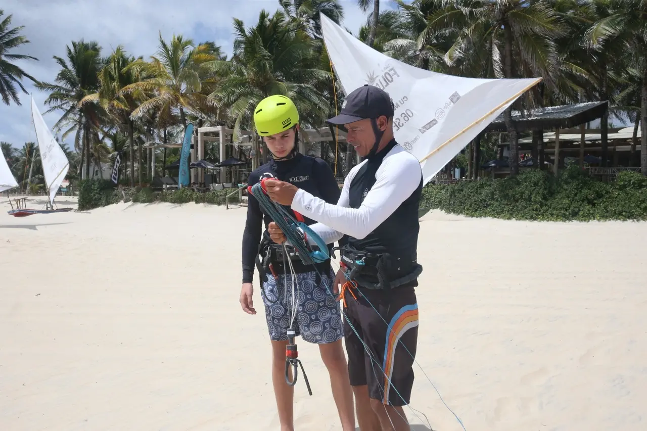 Instrutor dando noções básicas para aluno de kitesurf, ainda na beira da praia.