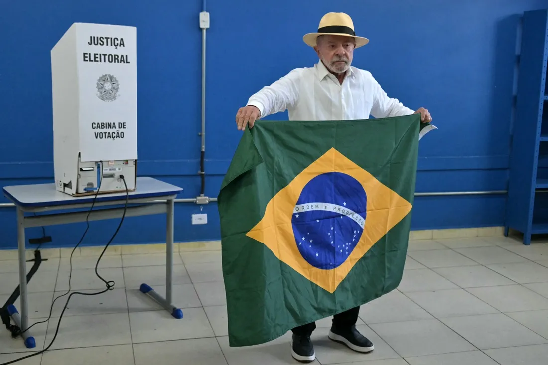 Ao deixar a urna, Lula posou para fotógrafos com a bandeira do Brasil.