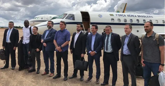 Jair Bolsonaro e membros da comitiva antes do embarque, no Brasil, sem máscara