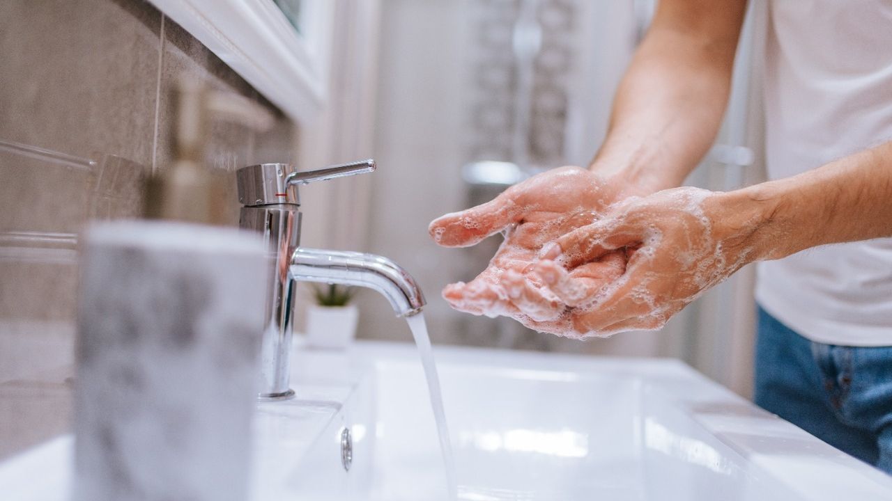 Homem lava as mãos em pia de banheiro