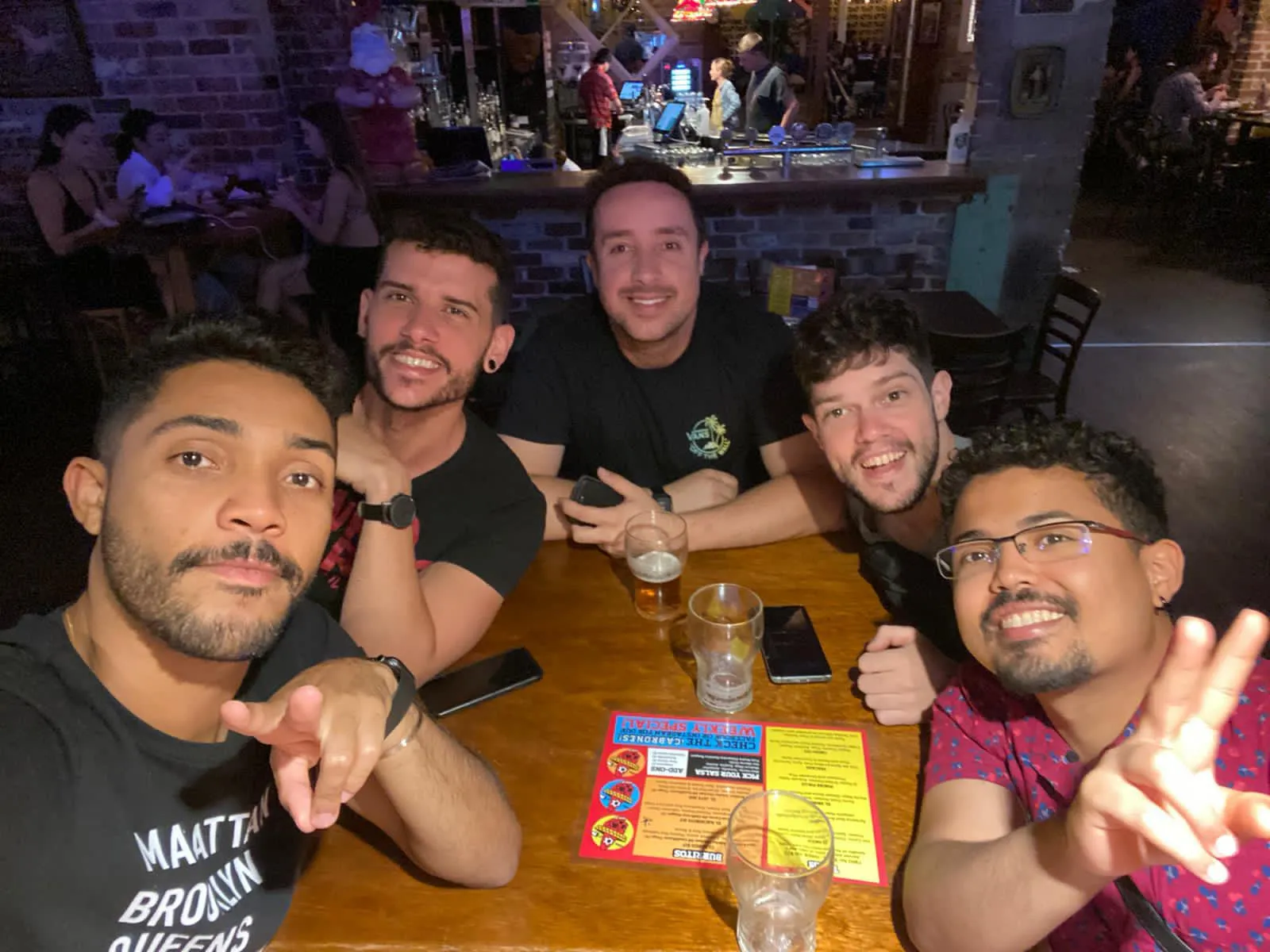 O designer de moda Lezio Lopes com amigos em bar na Austrália pós-pandemia.