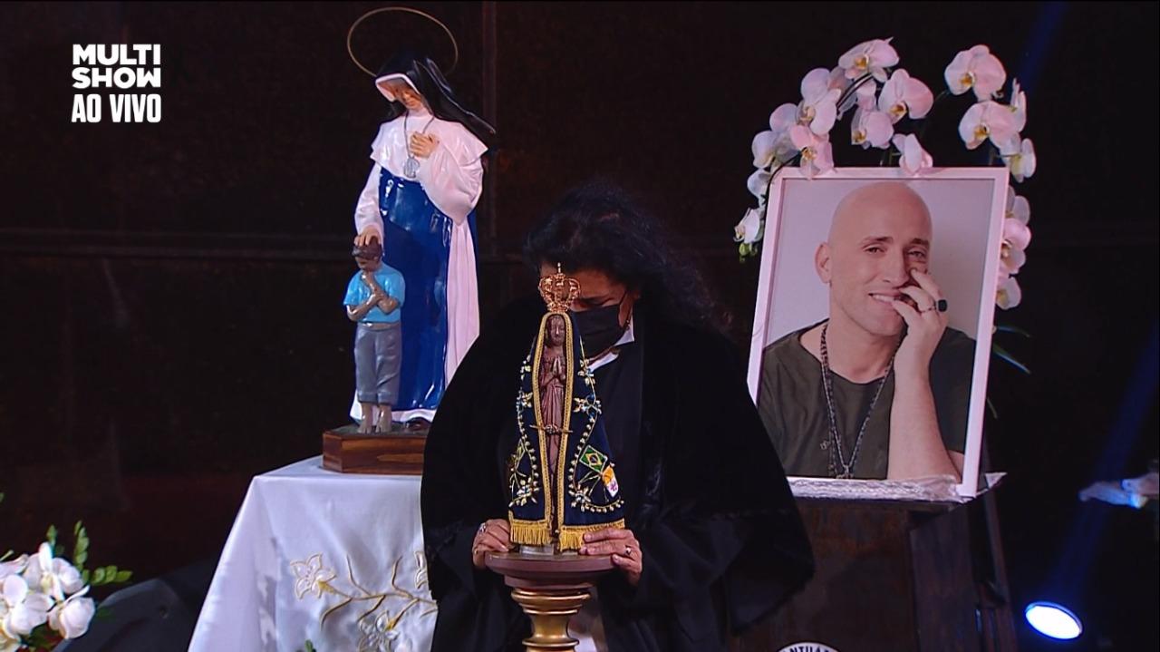 Regina Casé segurando imagem de Maria na missa de sétimo dia de Paulo Gustavo