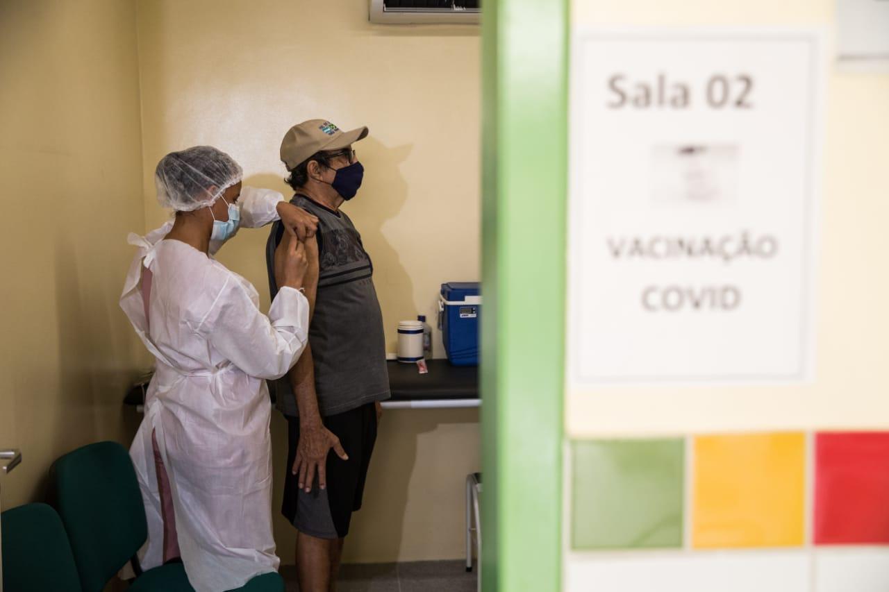 Idoso sendo vacinado contra a Covid-19 em sala de posto de saúde