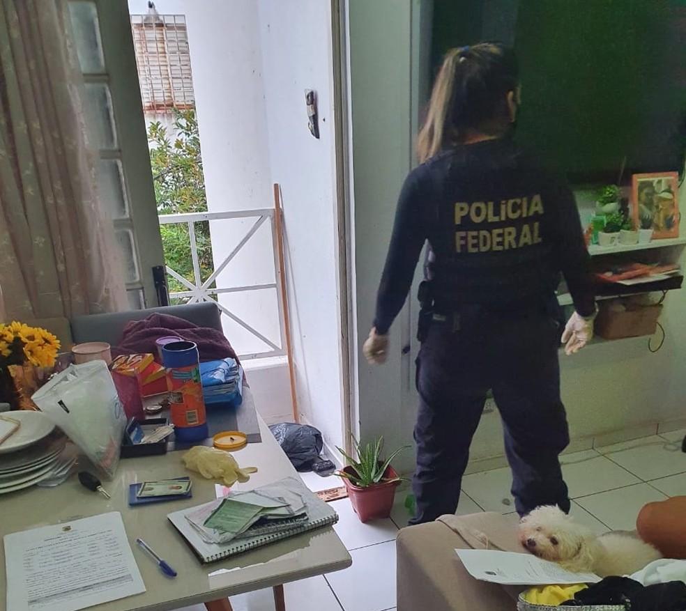 Agente mulher da PF em sala com documentos espalhados sobre uma mesa