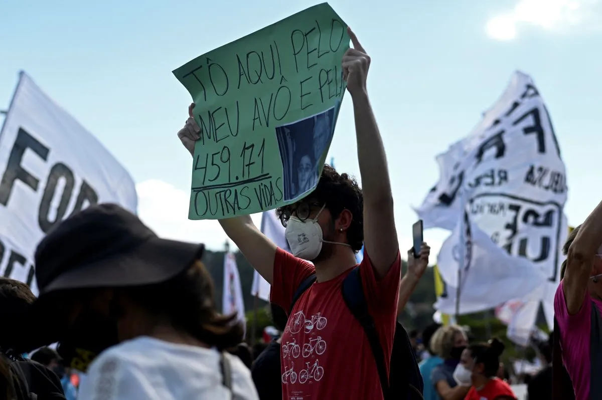 No RJ, jovem ergue cartaz indicando que está no protesto pela morte de seu avô e das mais de 450 mil mortes por Covid no País