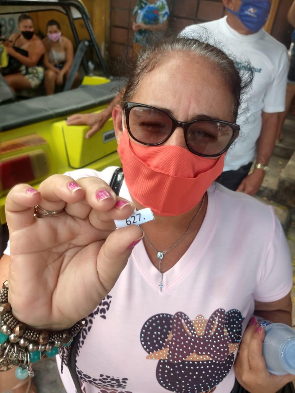 Mulher segura senha para vacinação contra Covid-19 em Cascavel