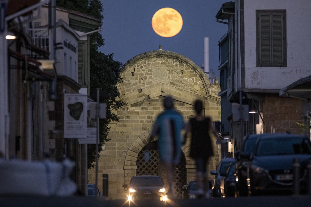 pessoas caminham sob a superlua crescente de morango em direção ao portão Famagusta, de construção veneziana, na antiga cidade murada da capital de Chipre, Nicósia