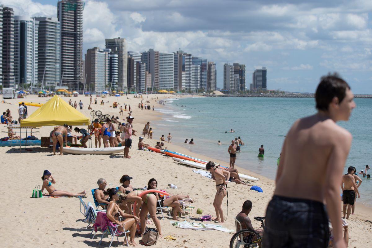 Pessoas na areia e dentro do mar de Fortaleza