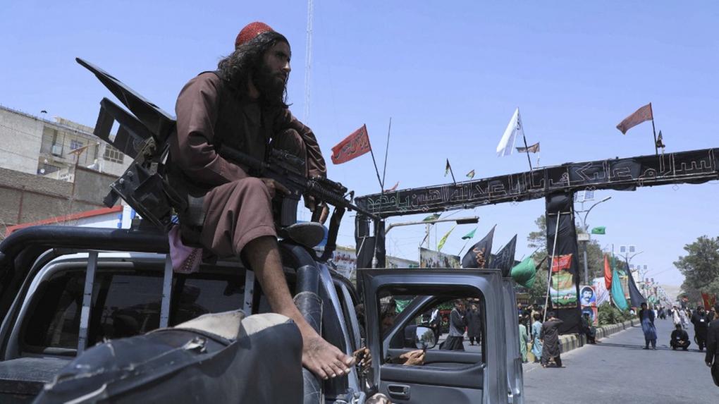 Membro do Talibã empunhando arma pesada sobre jipe