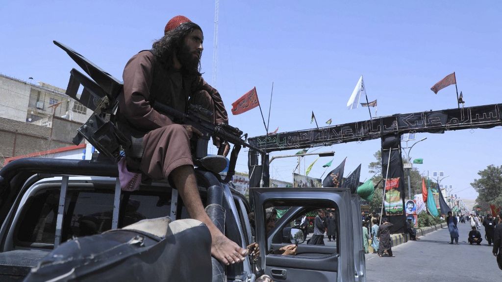 Membro do Talibã empunhando arma pesada sobre jipe