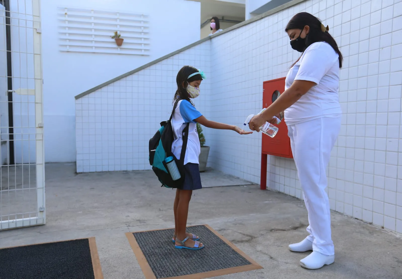 Estudantes passam por processo de higienização de pés e mãos ao chegar na escola municipal Madre Teresa De Calcutá, bairro de Fátima