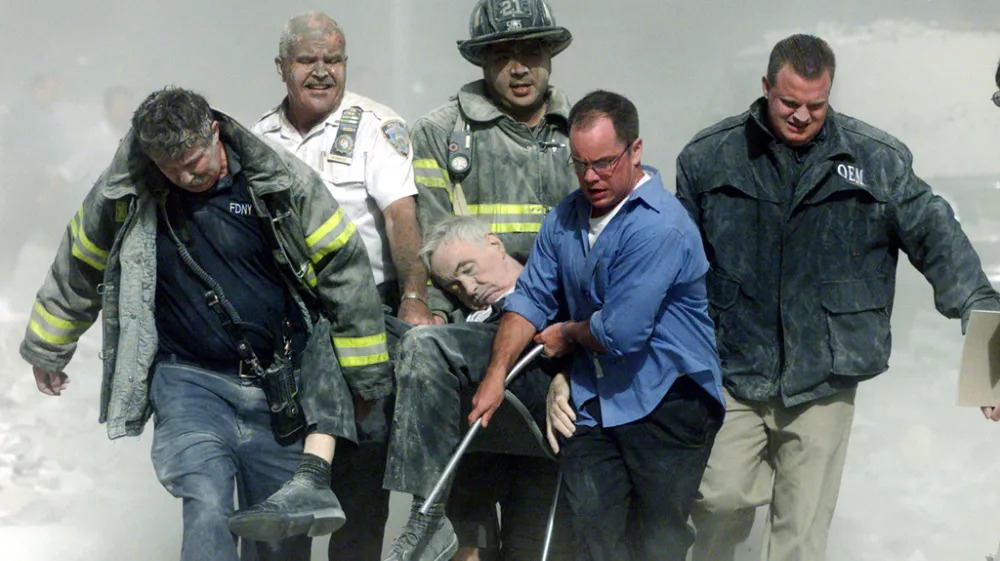 Carregado pelos bombeiros está padre Judge, um dos primeiros a chegar ao World Trade Center e acredita-se que o único sacerdote a entrar nas Torres Gêmeas naquele dia