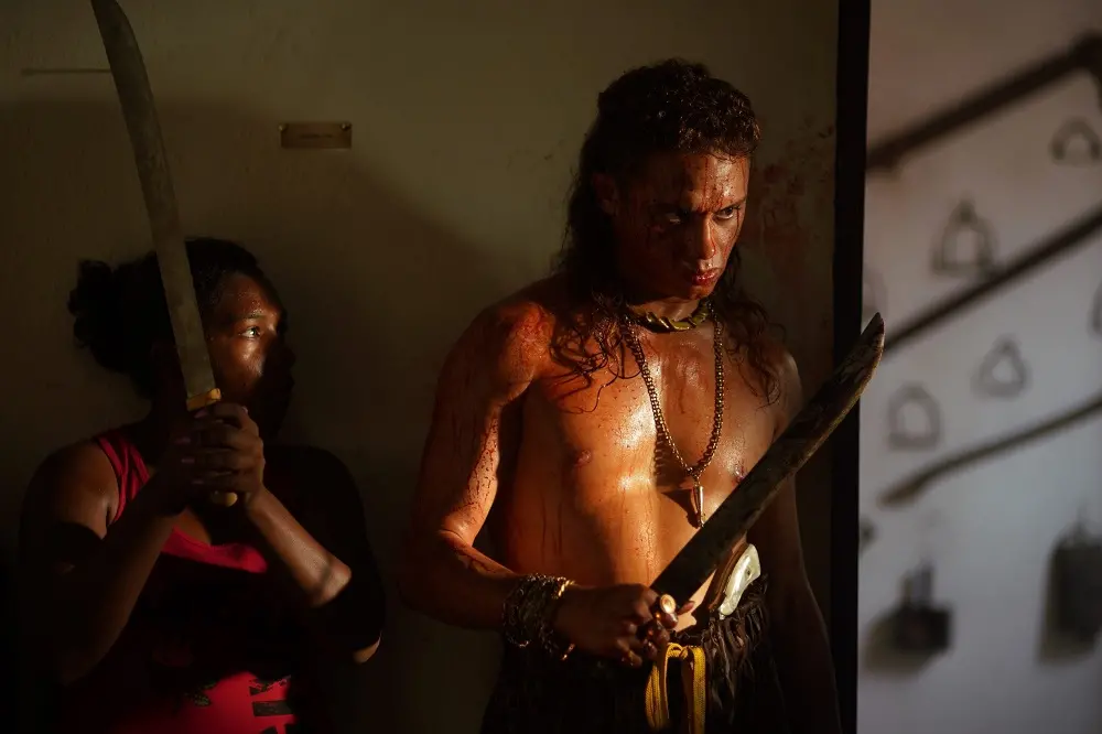 Cena do filme 'Bacurau', com o ator Silvero Pereira em destaque. Ele segura um facão e está ensanguentado, com uma feição de raiva.