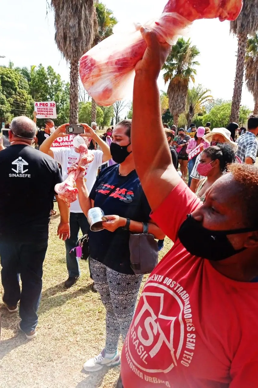 Membro do MTST com osso na mão faz manifestação em frente a casa do senador Flávio Bolsonaro