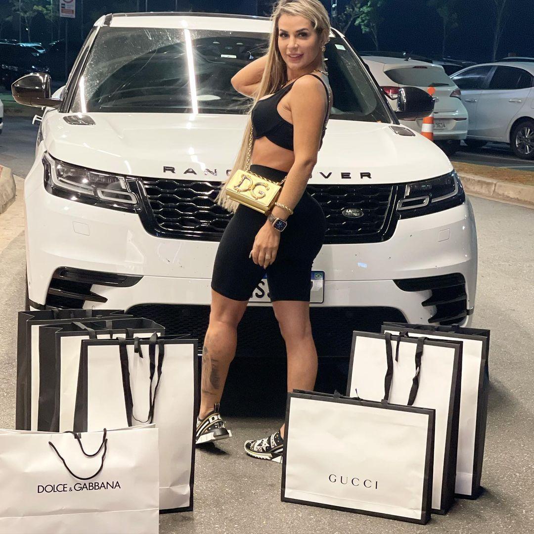 Deolane Bezerra em frente a carro Range Rover com sacolas de marcas de luxo