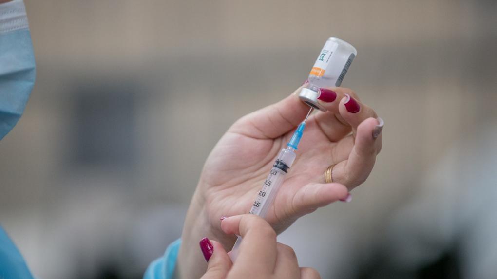 Imagem de uma mão com uma seringa e frasco com vacina de covid