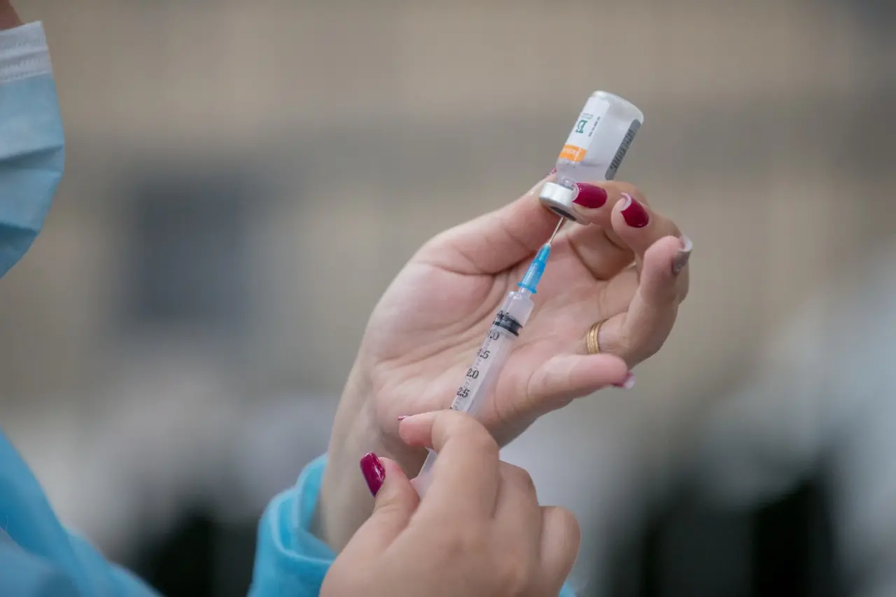 Imagem de uma mão com uma seringa e frasco com vacina de covid