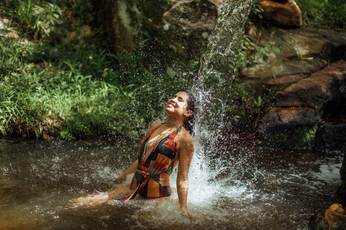 mulher tomando banho em bica de cachoeira em maragogi