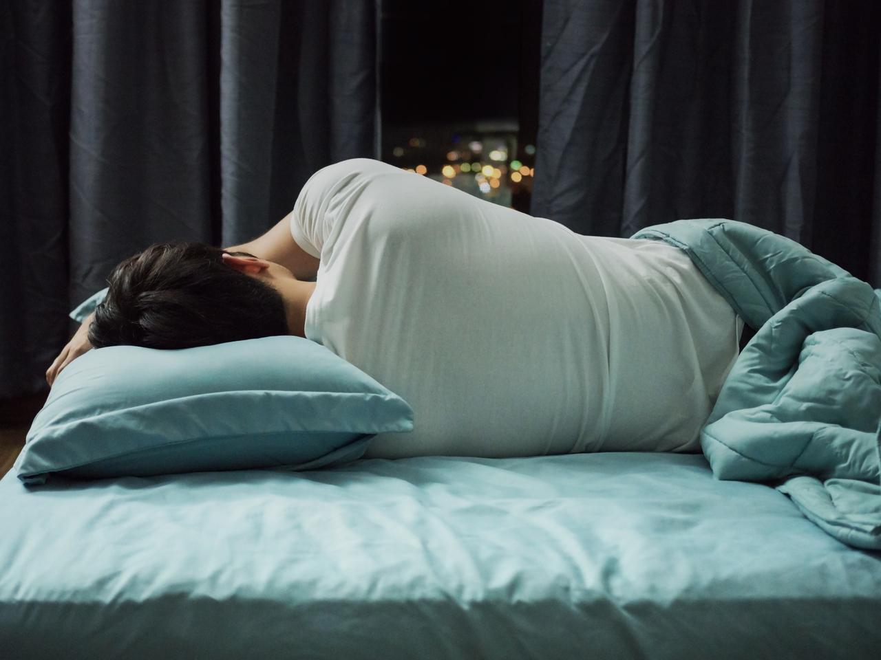 Homem dormindo em cama com lençóis azuis