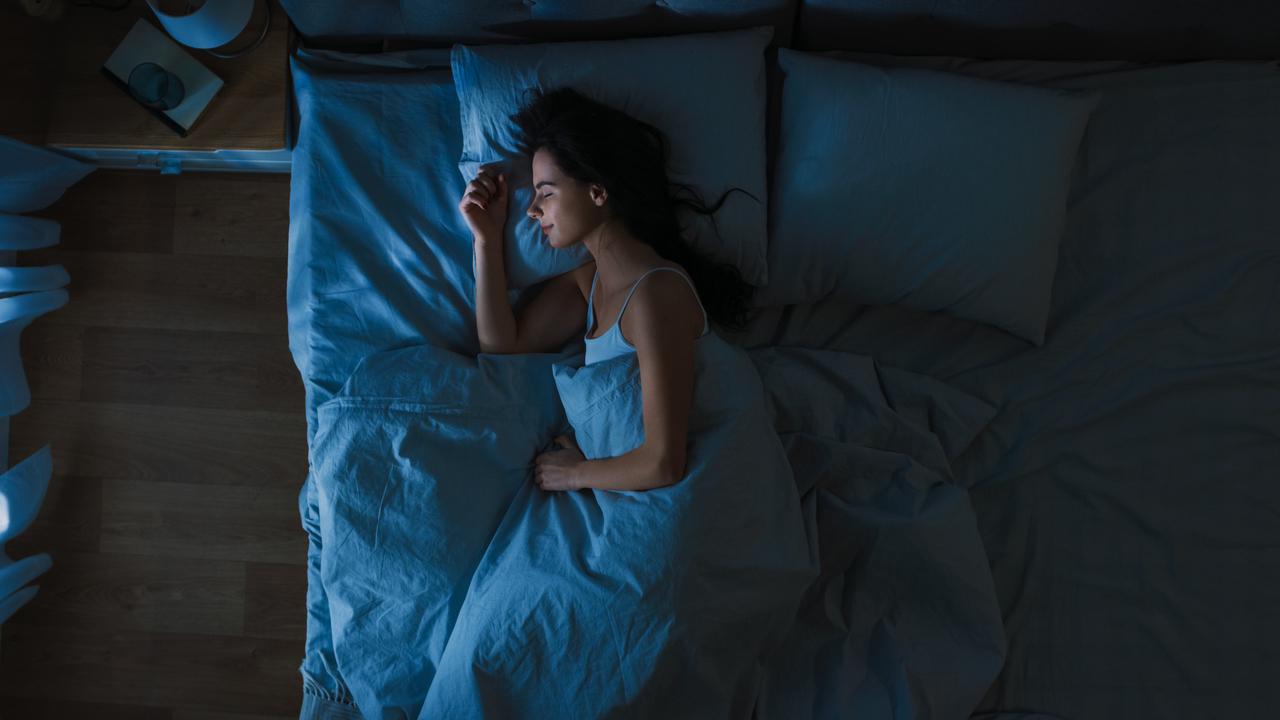 Mulher dormindo em cama com lençóis azuis