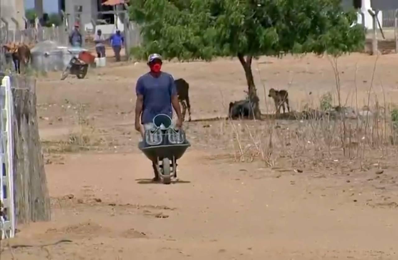 Homem leva vasilhames em carrinho de mão para pegar água no interior do Ceará