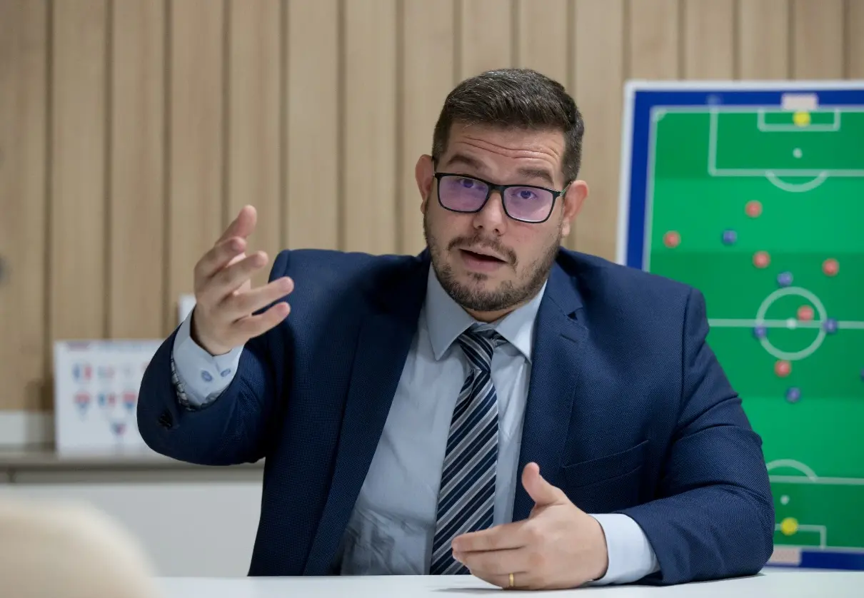 Alex Santiago concede palestra na frente de campo de futebol