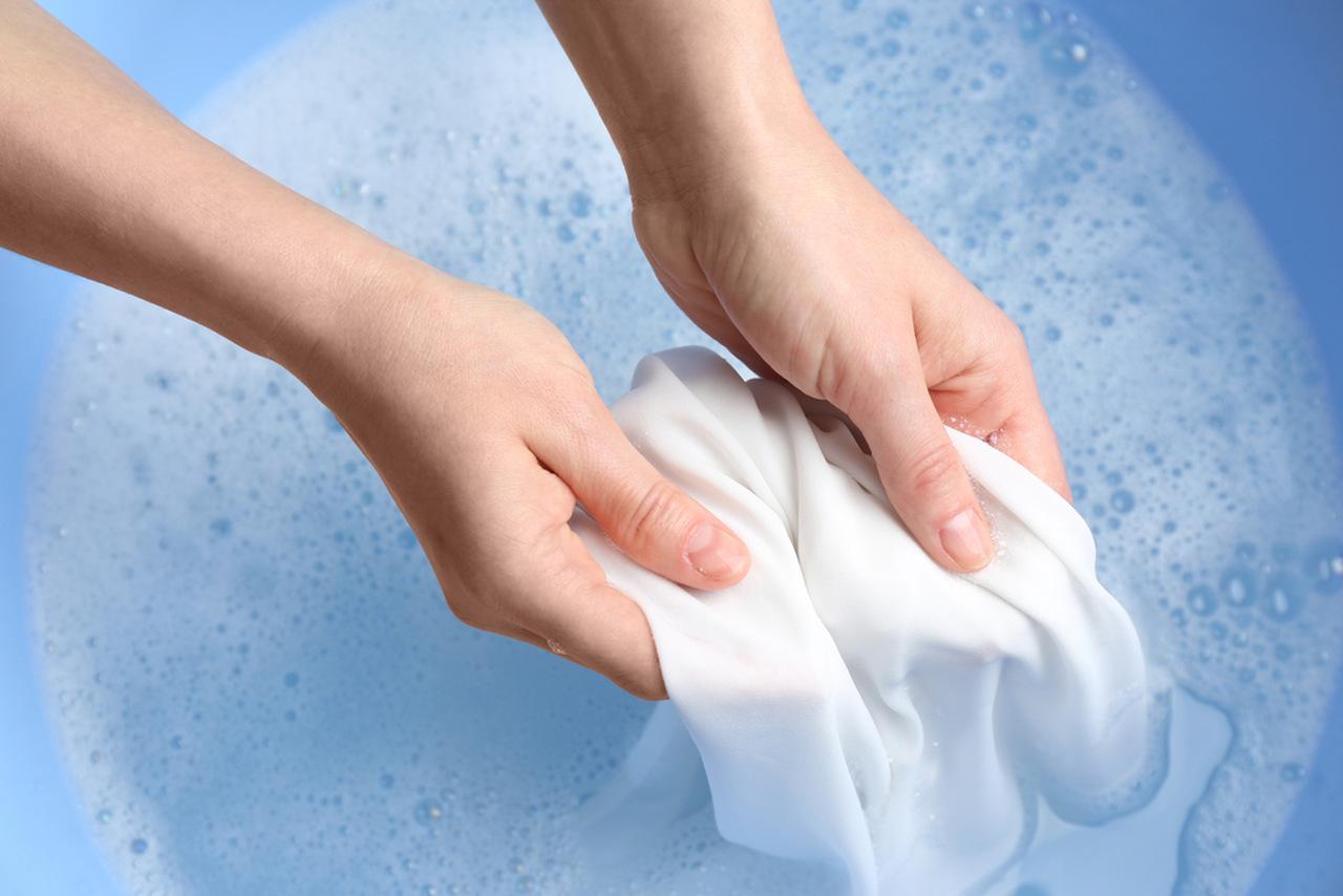 Pessoa lavando roupas com sabão líquido