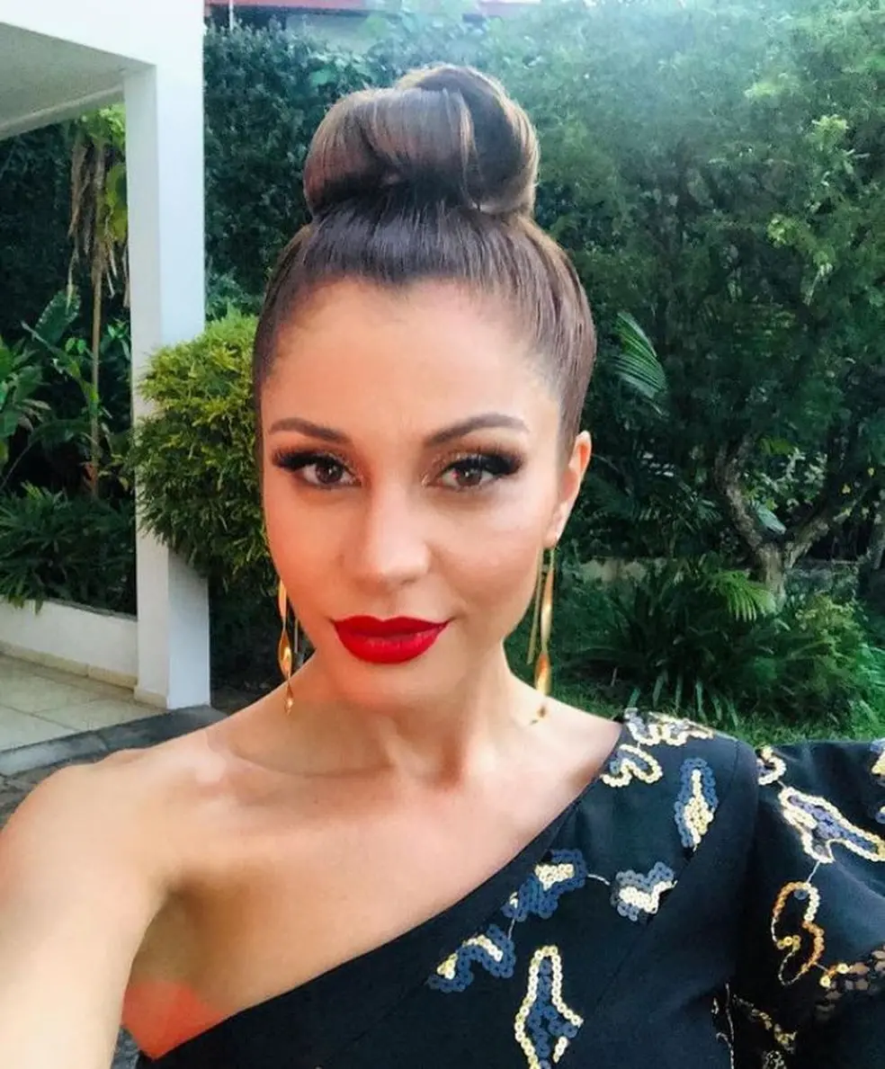 Maria Melillo com roupa preta e batom vermelho