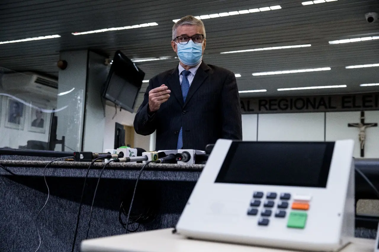 Desembargador Inácio Cortez em desfoque, e uma urna eletrônica no primeiro plano